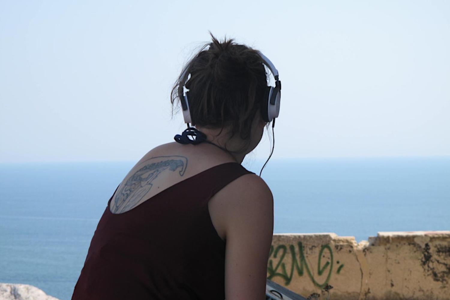 Une jeune femme écoute un podcast face au paysage